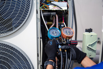 Air conditioner service .The air conditioner technician is using a gauge to measure the refrigerant pressure. air compressor.