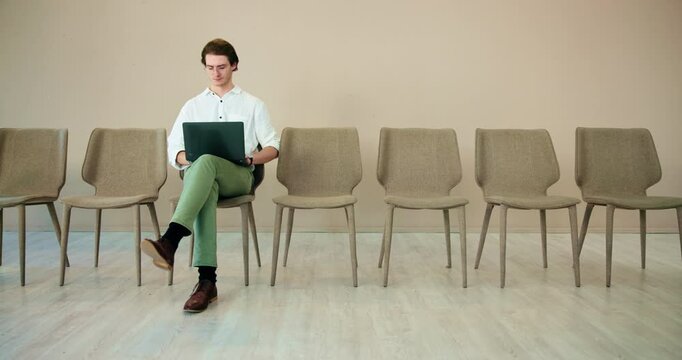 Waiting room, man and thinking with laptop for job interview, vacancy process and business hiring. Chairs, candidate or prepare with online cv for creative agency, recruitment or designer opportunity