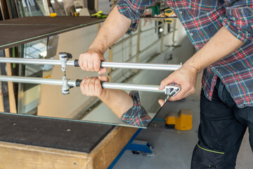 A glazier cuts glass sheets in a factory using a specialized hand cutter, Glass tools, Craft...