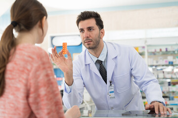Pharmacist male dispensing medicine to patient woman in drugs shop pharmacy