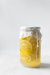 lemon cheong in a glass jar on a white background, korean lemon cheong in a transparent jar, lemon slices in sugar syrup