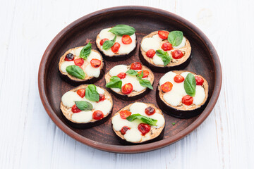 Italian mini pizza . Aubergine (eggplant ) with mozzarella cheese and basil . On rustic background