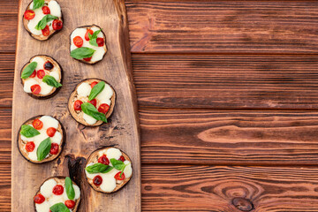 Italian mini pizza . Aubergine (eggplant ) with mozzarella cheese and basil . On rustic background