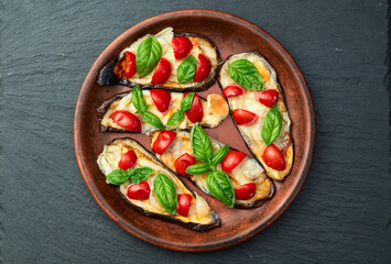 Italian mini pizza . Aubergine (eggplant ) with mozzarella cheese and basil . On rustic background