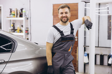 Confident Auto Mechanic Standing Beside Car in Garage Workshop with Tools