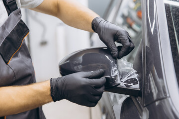 Close-Up of a Professional Applying Protective Film on a Car Mirror in an Auto Workshop