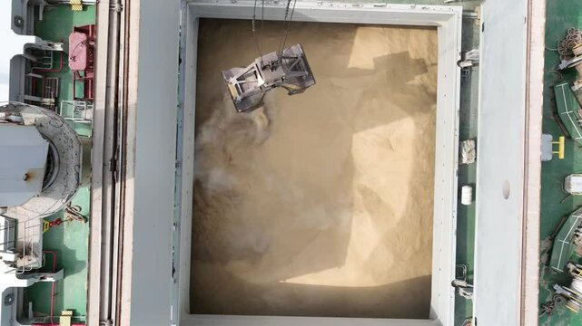 Loading dry cargo ship of wheat by cranes in port. Aerial view loading into holds of sea cargo vessel