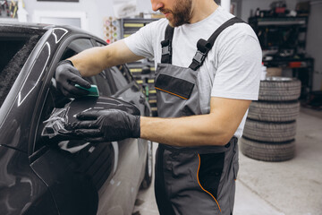 Close-Up of a Professional Applying Protective Film on a Car Mirror in an Auto Workshop