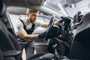 A mechanic's shop worker sitting in a car and checking on steering wheel on a car service.