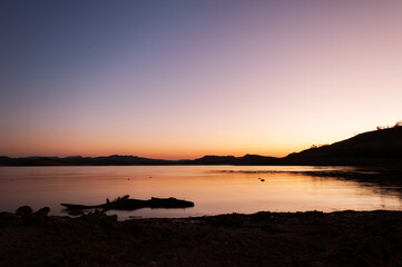 Fototapeta premium Vibrant sunset colors create tranquil atmosphere over lake, reflecting in calm water
