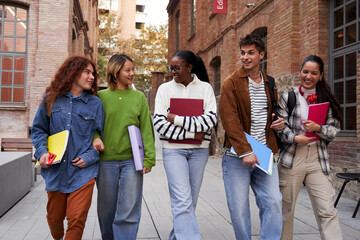 Internacional group of university students walking at school campus, talking and bonding while entering together to class. Image with copy space.