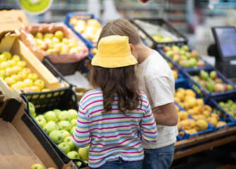 Kids little cute girl and teenager boy shopping for fresh organic fruits and vegetables in supermarket