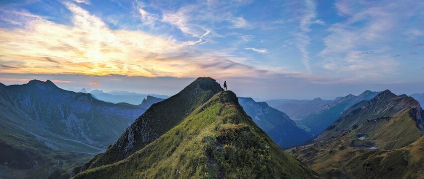 Sunset on the Lauiberg above the Muotathal and Richisau Glarus. Beautiful ridge hike to the summit. Woman hikes to the summit cross in a beautiful evening atmosphere. High quality photo.