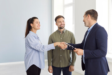 Realtor or agent shakes hands with a couple to confirm the agreement for purchasing or renting a...