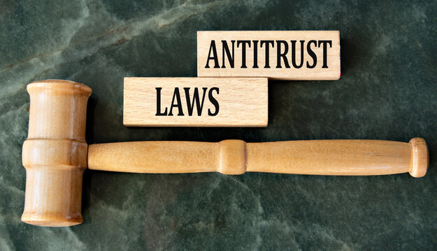 ANTITRUST LAWS - words on wooden blocks on a green background with a judge's gavel