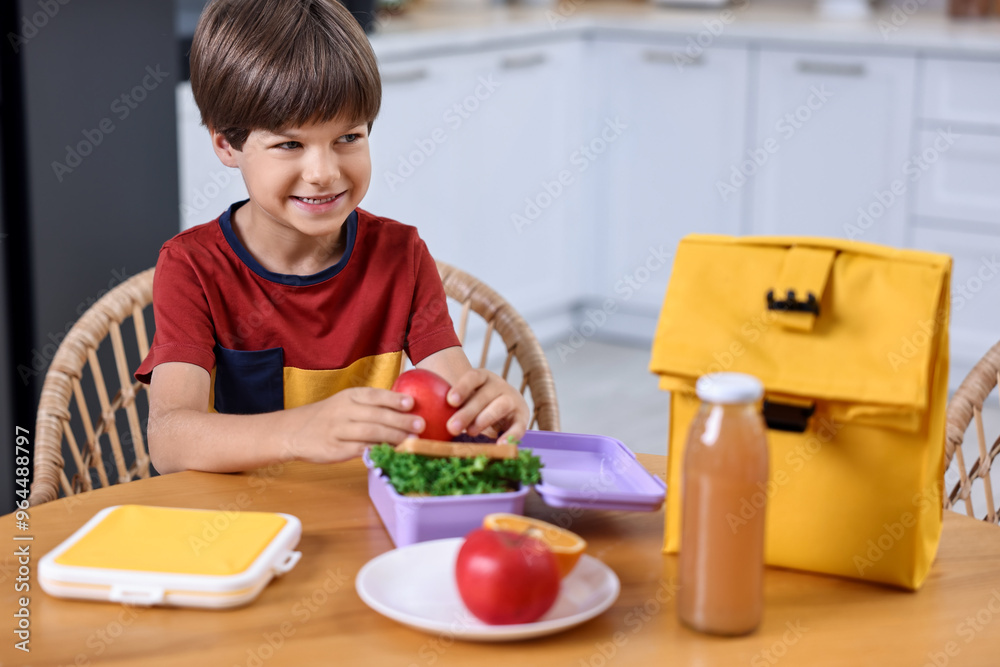 Wall mural Cute boy with lunch box, healthy products and bag at wooden table in kitchen