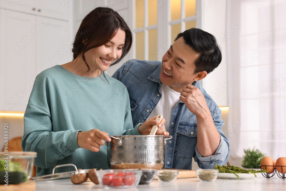 Wall mural happy lovely couple cooking together in kitchen