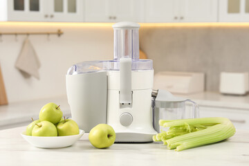 Modern juicer, celery and apples on white marble table in kitchen
