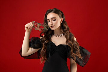 Naklejka premium Beautiful woman with carnival mask on red background