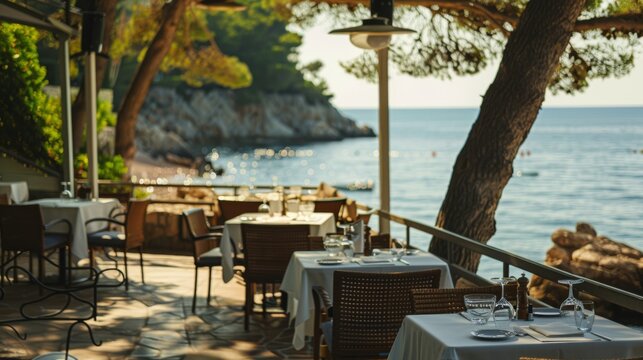 A peaceful seaside restaurant with elegantly set tables overlooking a picturesque ocean view, perfect for a serene dining experience.
