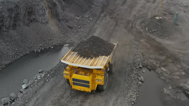 Large quarry dump truck. Loading rock in dumper. Loading coal into truck. Mining car machinery to transport coal. Open pit mine quarrying extractive industry stripping work. Big Yellow Mining Trucks