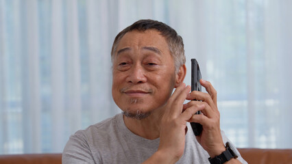 Blind Asian elderly men use digital assistant get ease of access functions on smartphone, Voice typing on phone. Person visually impaired and eye disease in the elderly Concept, Accessibility phone.