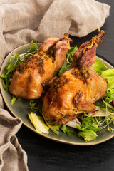 Baked tasty quails on ceramics plate with salad