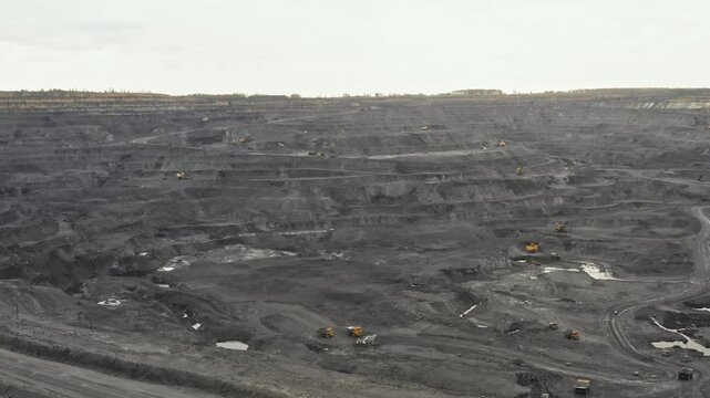 Panorama aerial view shot, open pit mine, coal mining, dumpers, quarrying extractive industry, stripping work. View from drone at opencast mining with lots of machinery trucks