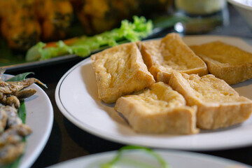 Tahu goreng or fried tofu prepared in white plate. Asian dish and Indonesia local food.