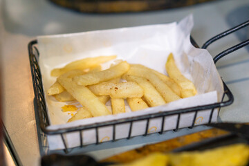 French fries on black basket. Restaurant menu meal. Fast food full of fat and calories