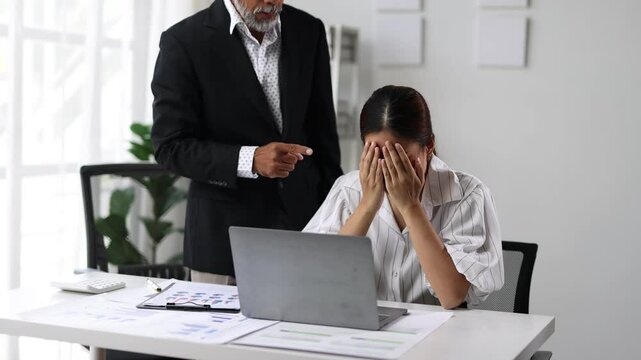 Stressed businesswoman reacts to supervisor's criticism in office. Struggling, she buries her face in hands, showing signs of pressure and frustration.