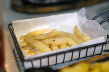 French fries on black basket. Restaurant menu meal. Fast food full of fat and calories