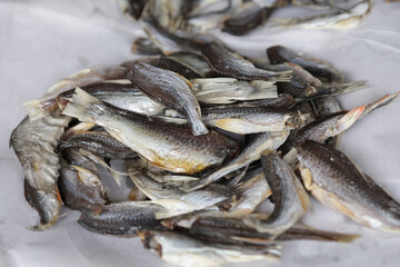 Dried fish are piled up on white paper. Dried fish is a good source of calcium.