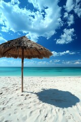 Sunny beach with clear sky, turquoise water, and thatched umbrella casting a shadow on white sand.