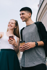 Positive millennial male and female friends discussing some things during positive meeting for communicate on leisure, happy Caucasian hipster guys talking while have coffee break outdoors