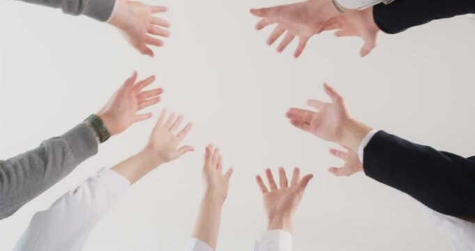 Group of a business people joining hands in stack. Close up of company employees putting their arms in a pile together. The concept of unity and teamwork. Low angle view. 4k video. Slow motion video.