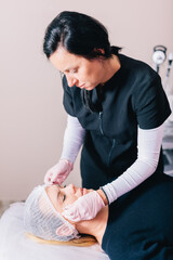 Beautician measuring for eyebrow geometry, shaping or lamination cosmetic procedure on woman's face...