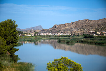 Ojos Reservoir, in the Ricote Valley, Region of Murcia, Spain, with the calm waters reflecting the mountains
