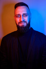 Fototapeta premium Studio portrait with colorful light of young handsome bearded man.