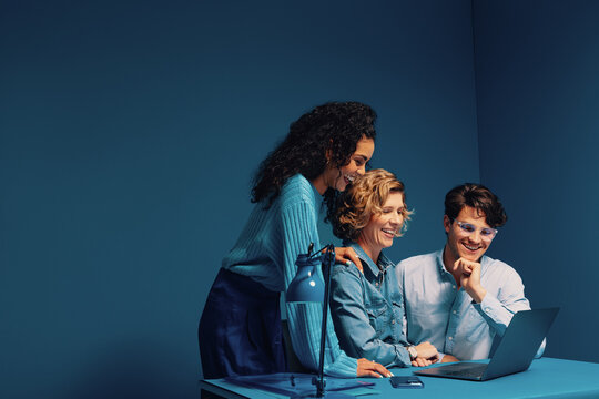 Creatives working together on laptop in monochromatic office setting