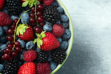 Mix of ripe colorful berries in bowl photography . Blueberry , strawberry , raspberry , blackberry and red currant . Top view