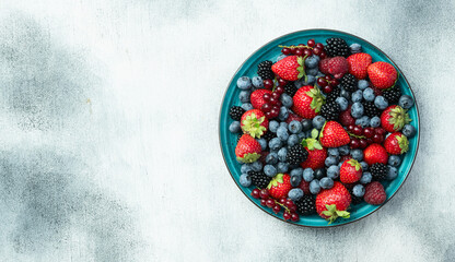 Mix of ripe colorful berries in bowl photography . Blueberry , strawberry , raspberry , blackberry and red currant . Top view