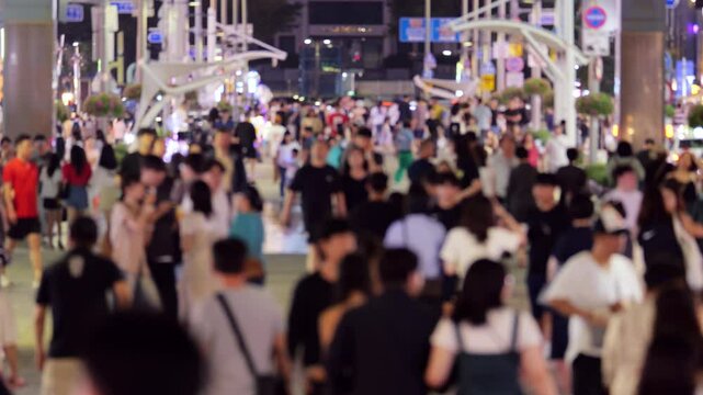 Blurred view along famous pedestrian street Gunam in Haeundae district of Busan, in late evening. Numerous local and foreign tourists stroll along walking street lined with restaurants and cafes.