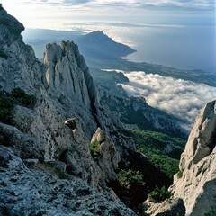 Fototapeta premium The jagged peaks of Mount Ai-Petry, Crimea, with a sea of clouds below and the coastline visible in the distance