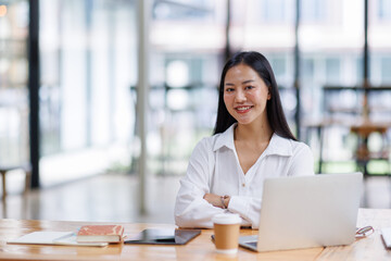 Asian Businesswoman Using laptop computer and working at office with calculator document on desk, doing planning analyzing the financial report, business plan investment, finance analysis concept.
