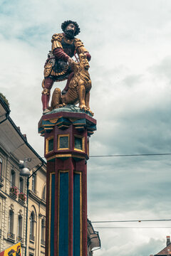 Bern, Switzerland - July 22, 2024: Simsonbrunnen fountain features a biblical samson killing a lion, in the crowded Marktgasse, one of the main streets in Bern