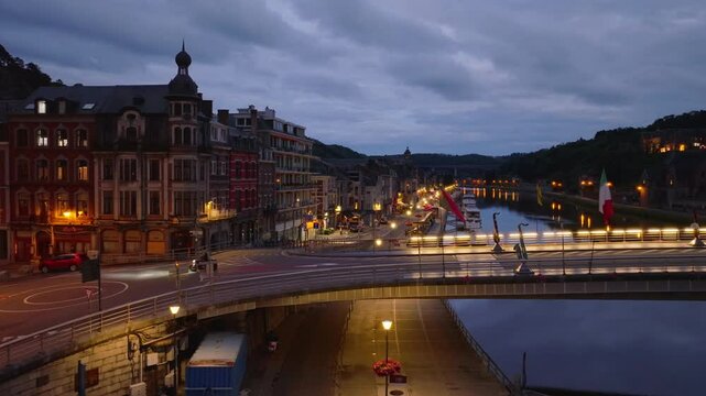 Tranquil aerial views capture the glowing cityscape of Dinant, Belgium, featuring bridges over the Meuse river as the sky shifts from dusk to night
