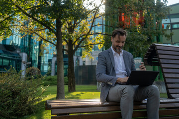 Obraz premium Businessman using a laptop while sitting outside his office building