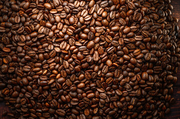 Large pile of coffee beans spilled on wooden table