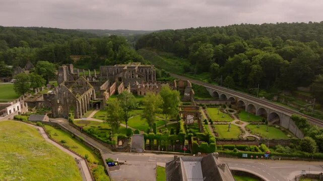 Villers Abbey ruins stand amidst lush greenery. Camera pans across, capturing the serene beauty of the remnants